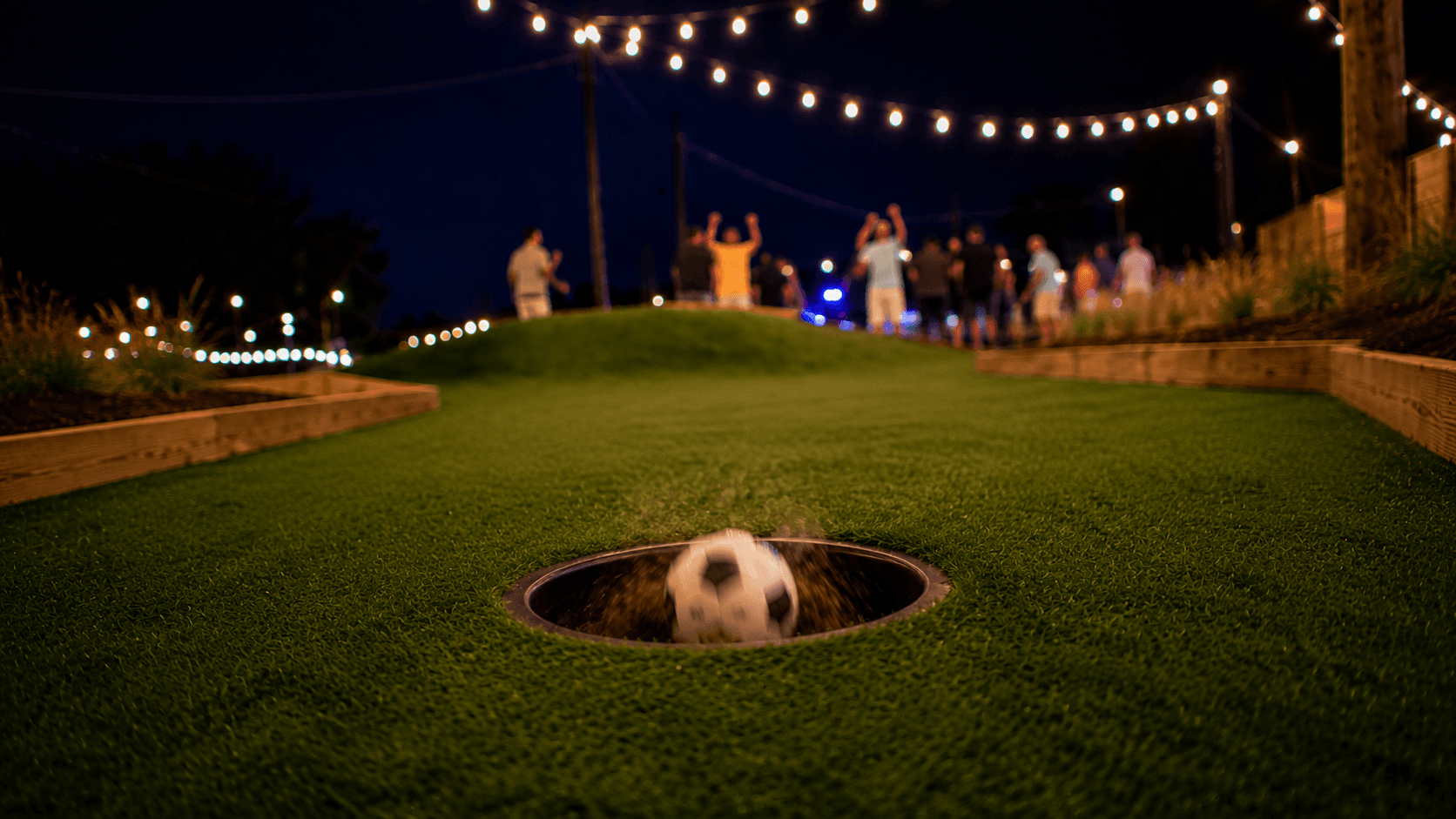Soccer ball dropping into circular ground hole with players celebrating